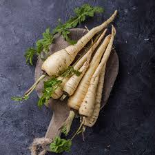 all american parsnips with green tops on a dark surface