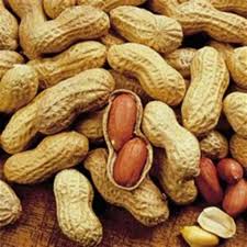 Close-up of peanuts with a few cracked open on a wooden surface