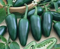 Green peppers with leaves on a wooden surface