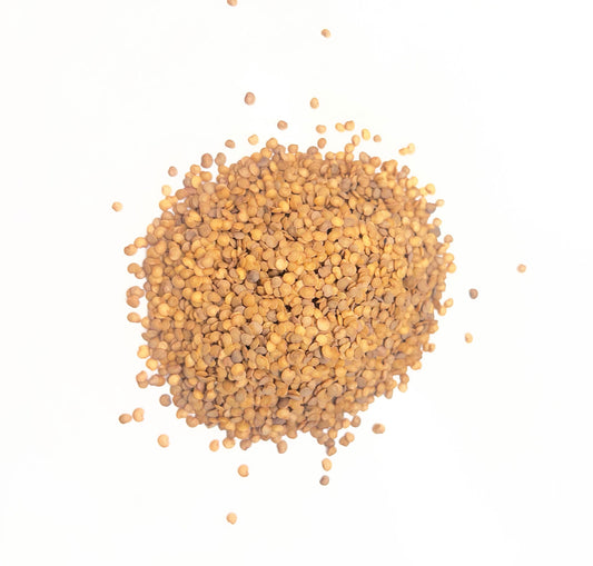 Heart-shaped pile of light brown seeds on a white background